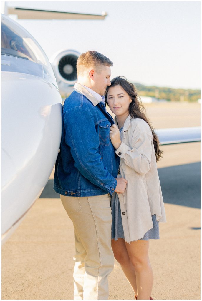 couple posing next to private jet 