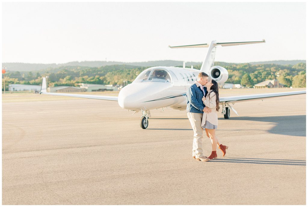 guy and girl kissing in front of airplane