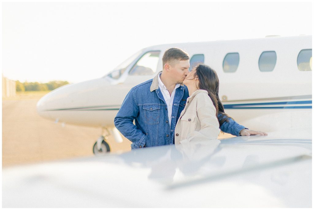 couple kissing in front of airplane wing