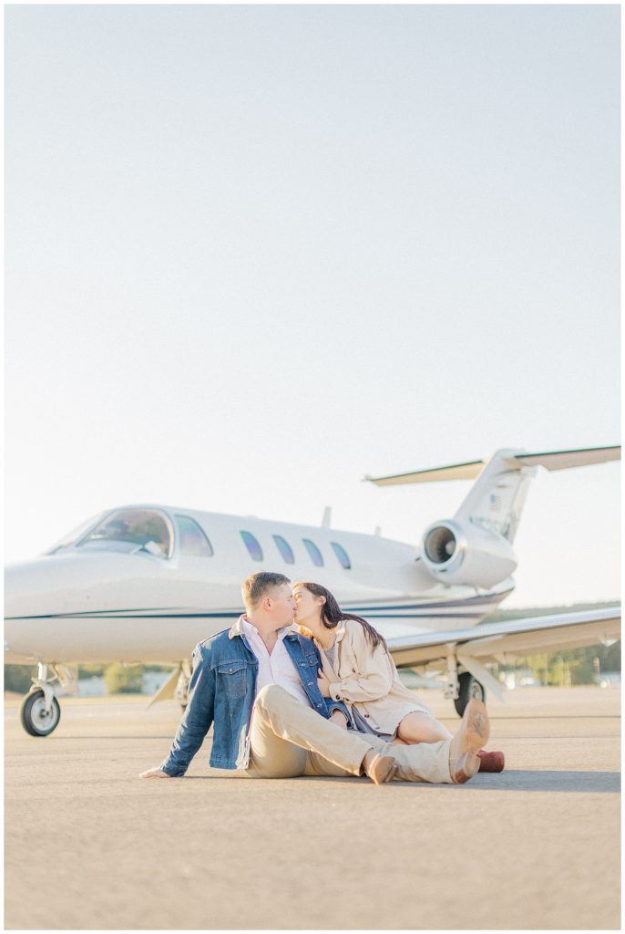 couple kissing in ground in front of airplane